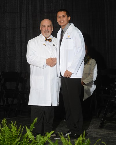 Photo of Roberto Tellez receiving his white coat.