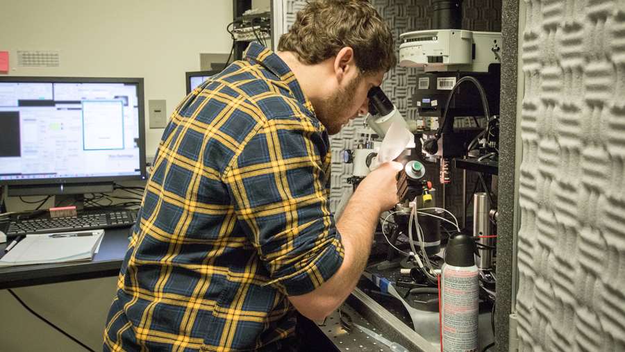 Neuroscience graduate student, Mason McCollum, working with a microscope