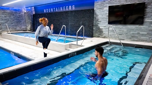 Female athletic training student trains with student in pool