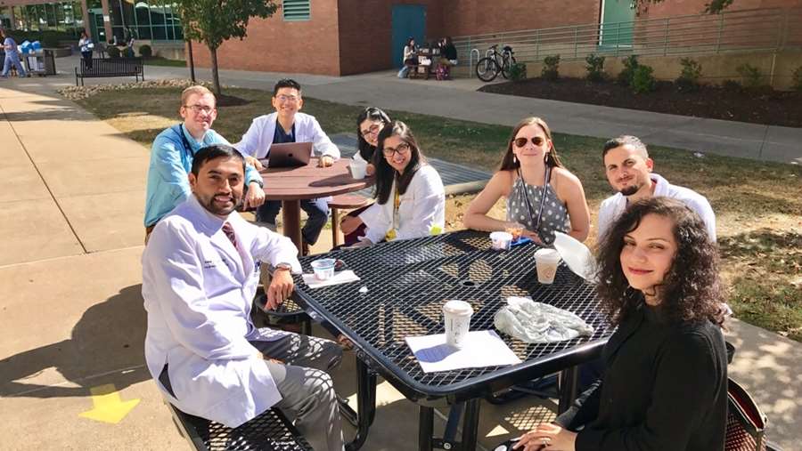Fellows gather to eat lunch together outside. 