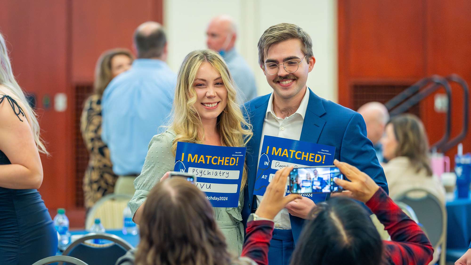 Medical students pose with signs after learning where they matched.