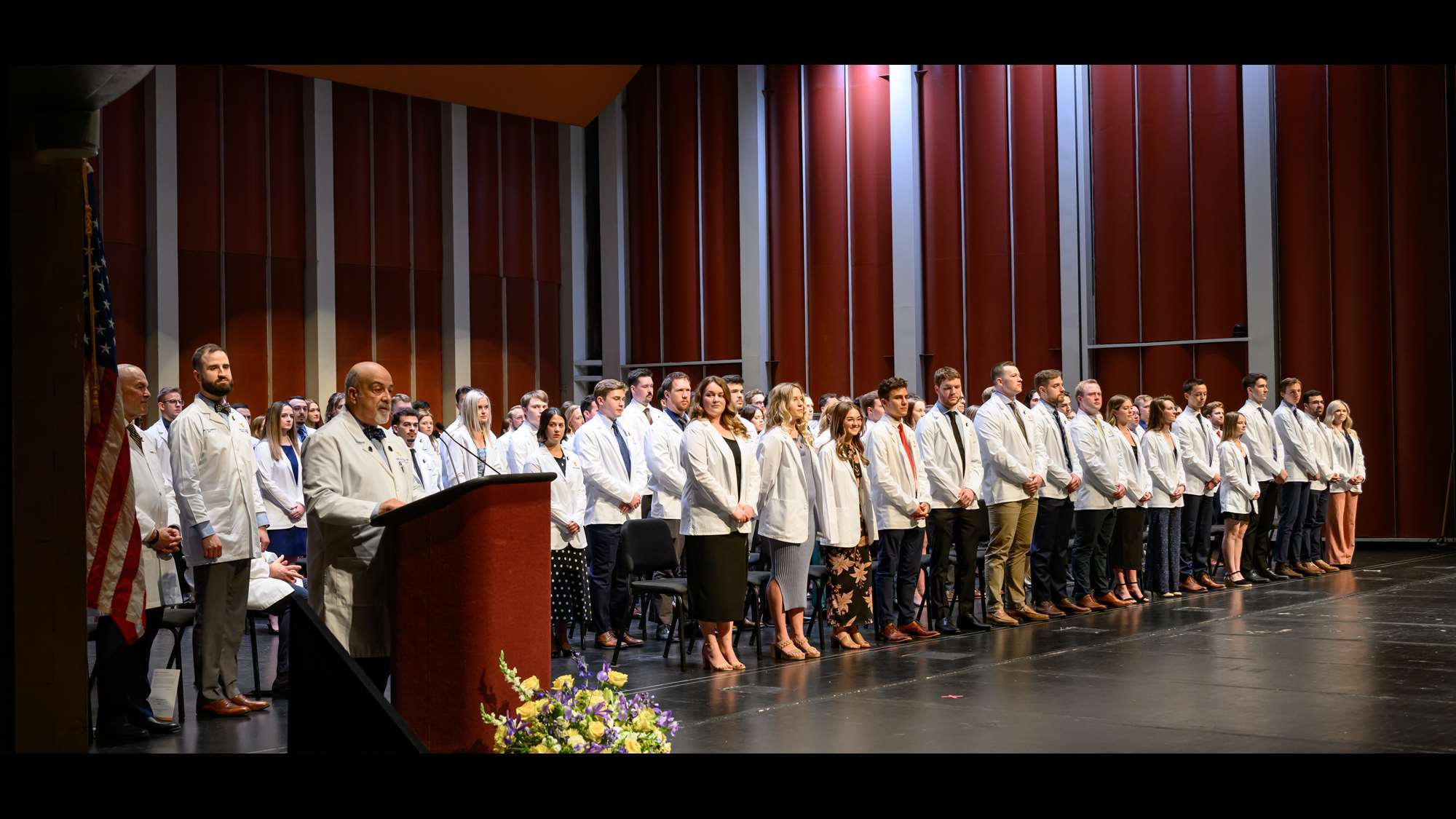 Second year medical students stand after receiving their white coats.