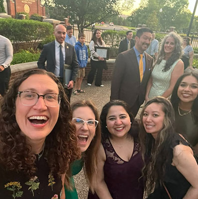 Residents gathering for a group selfie with other onlookers in the background holding degrees.